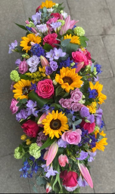 Sunflower and Rose Casket Spray - A beautiful selection of sunflowers and roses with a selection of complimenting bright seasonal flowers, creating a stunning celebration of life tribute. Standard size 3ft, medium 4ft, large 5ft. Hand delivered by your local florist Susettes flowers.