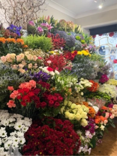 Christmas Florist Choice Hand tie - A gorgeous selection of Christmas flowers and seasonal foliage, beautifully gift wrapped and presented in water.